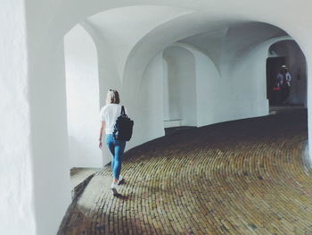 Rear view of backpack woman walking in corridor