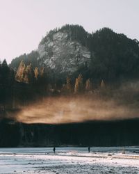 Silhouette trees by lake against sky during winter