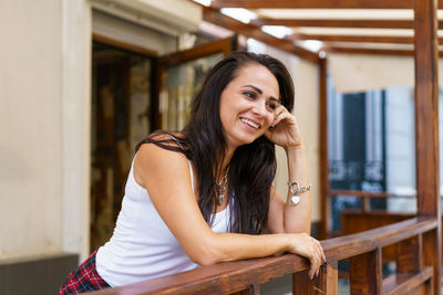 Young caucasian woman is smiling standing on porch near door of store in casual