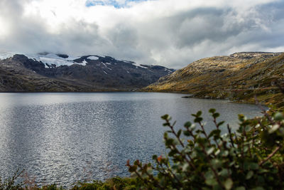 Scenic view of mountains and lake against cloudy sky