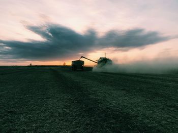 Windmills on field against sky at sunset