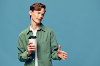 Young man standing against blue background