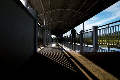 Rear view of silhouette mid adult man walking in covered bridge