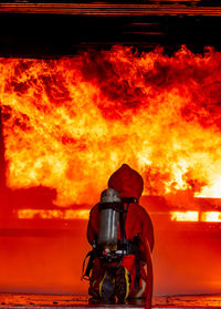 Rear view of man with fire hydrant against orange sky