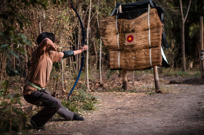 Side view of woman photographing against trees