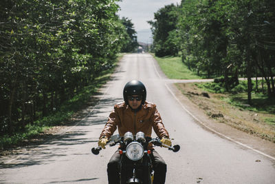 Portrait of man riding motorcycle on road in city