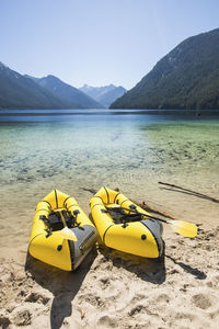 Two packrafts on the shore of a turquoise lake,