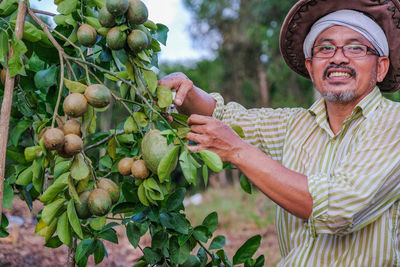 Portrait of smiling man standing by tree