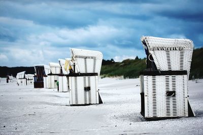 Hooded chairs at beach against sky