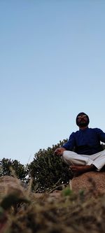 Man sitting against clear blue sky