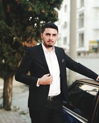 Portrait of businessman standing by car