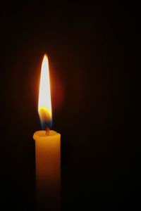 Close-up of lit candle in darkroom