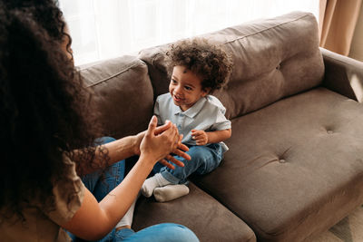 Happy mother and son sitting on sofa at home