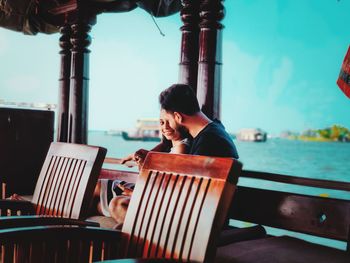 Man using mobile phone while sitting on deck chair