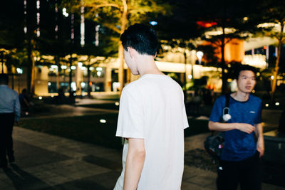 Rear view of man standing on street at night