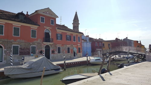 Boats moored in canal by buildings against sky in city