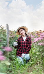 Portrait of smiling young woman with flowers against sky