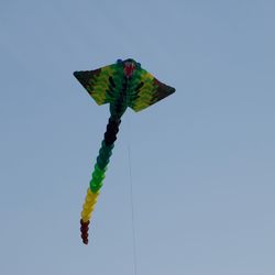 Low angle view of kite flying against clear blue sky