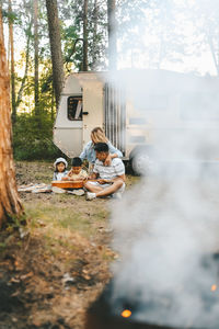 An asian family is vacationing traveling on a road trip by a camper car in the forest in nature