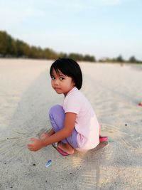 Portrait of girl crouching at beach