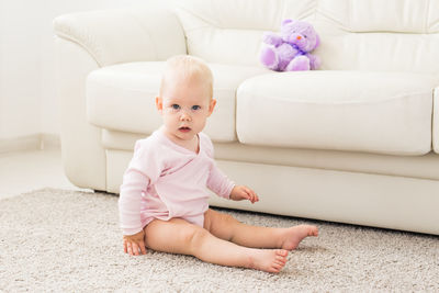 Cute baby girl sitting with toy at home