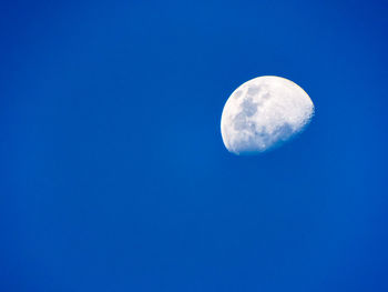 Low angle view of moon against clear blue sky