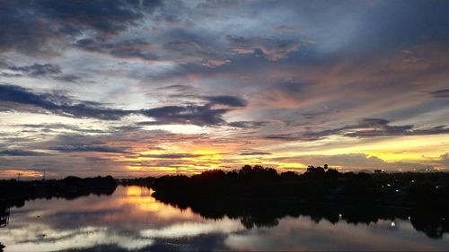 Scenic view of lake against dramatic sky during sunset