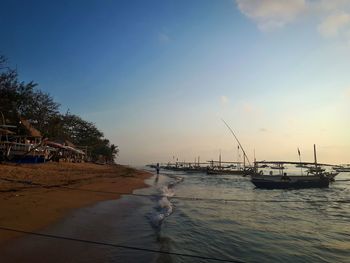 Sailboats moored on beach against sky during sunset
