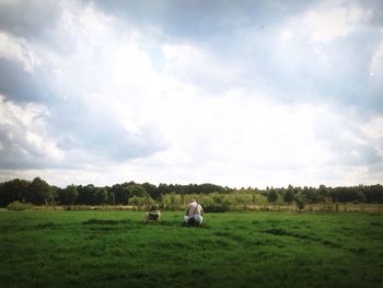 Scenic view of grassy field against cloudy sky