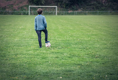 Rear view of boy standing on soccer field