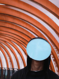 Front view of a mirror face man against an orange background