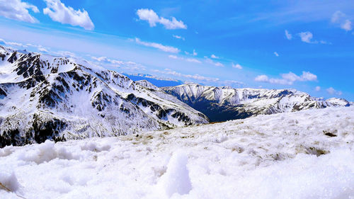 Snow covered landscape against blue sky