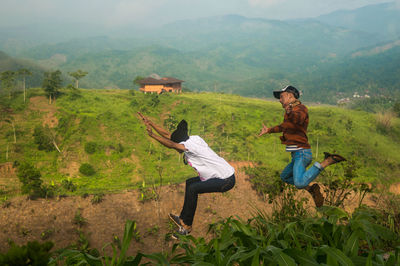 People jumping over plants against mountains