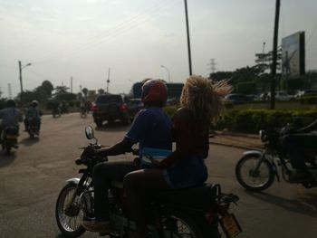 Rear view of people riding bicycle on road