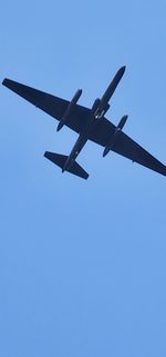 Low angle view of airplane flying against clear blue sky