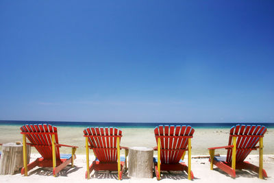 Chairs on beach against clear sky