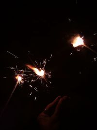 Person holding illuminated firework display at night