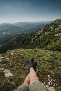 Low section of man on mountain against sky