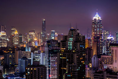 Illuminated buildings in city against sky at night