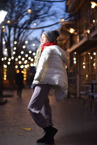 Woman in warm clothes while standing on sidewalk in city