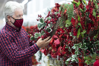 Senior man wearing mask touching berries