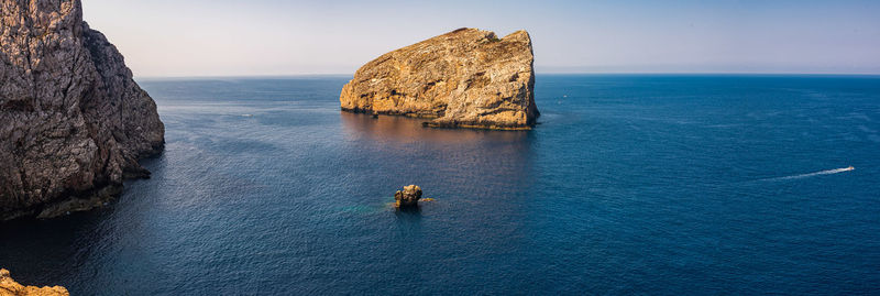 Aerial view of rock formations in sea against clear blue sky