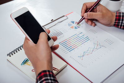 Low section of person using mobile phone on table