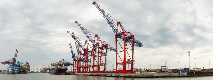 Cranes at commercial dock against sky