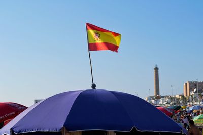 Low angle view of flags against clear blue sky