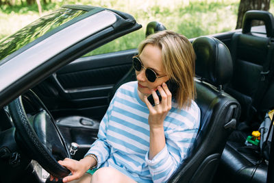 A woman is driving a convertible car. summer road trip to nature