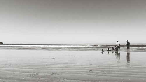 People on beach against clear sky