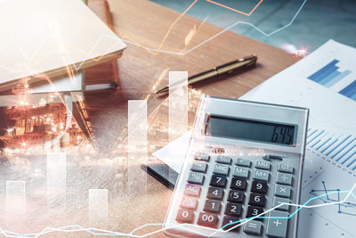 Double exposure of graphs with calculator and book on table