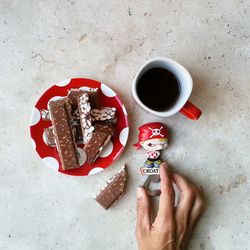 Directly above shot of hand holding coffee cup on table