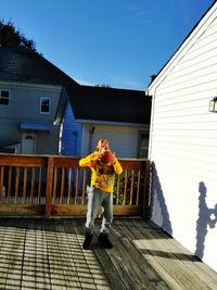 Woman standing outside house against sky